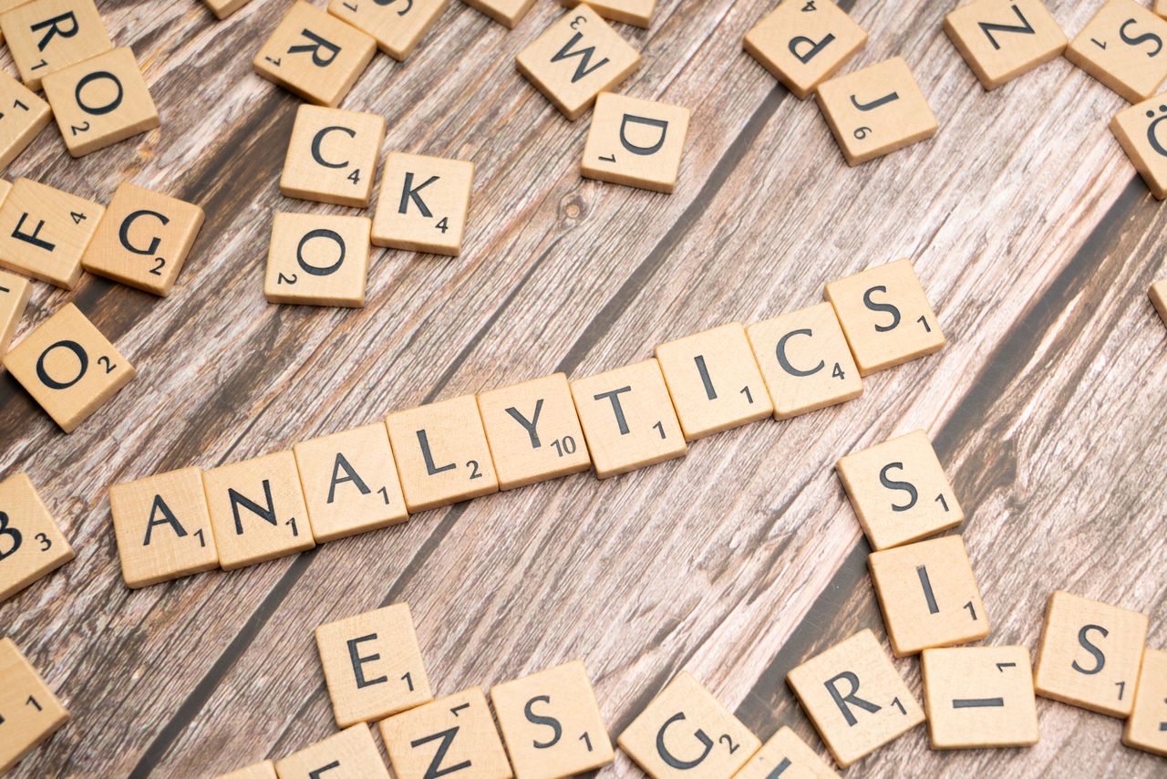 heros-img Scrabble tiles spelling Analytics on a wooden surface, symbolizing data analytics concept.